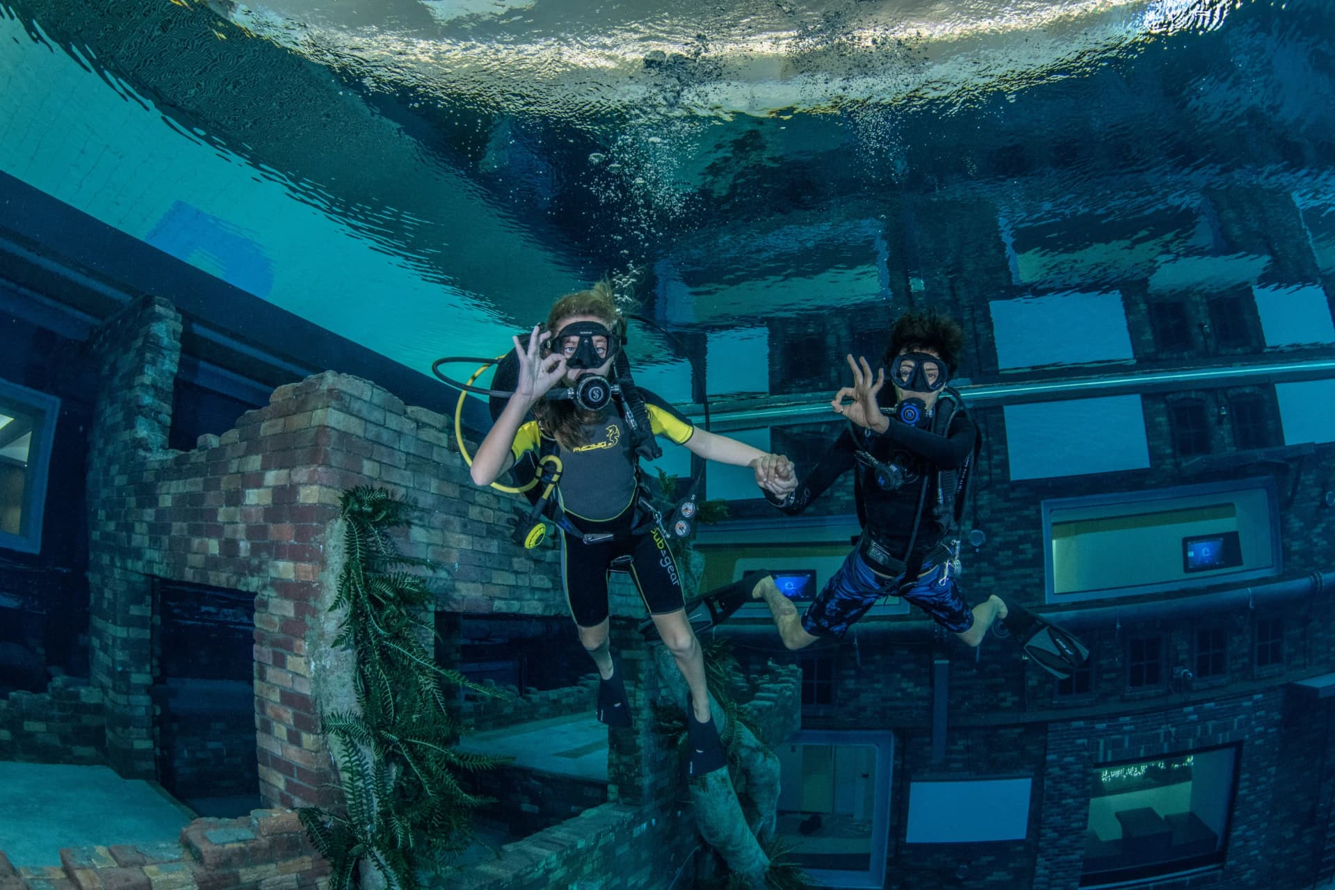 Daring divers exploring Deep Dive Dubai pool