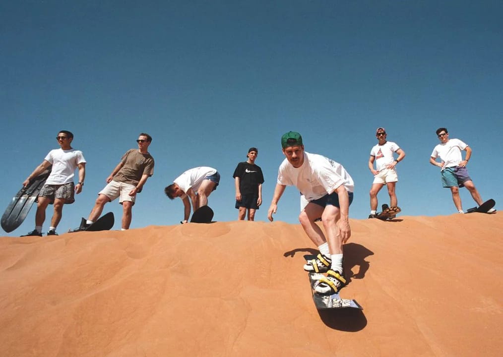 Men enjoying sandboarding in Dubai desert